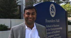 Dr. Hari Rajagopalan stands in front of Founders Hall sign